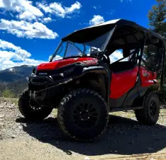 A red and black four wheeler parked on top of a hill.