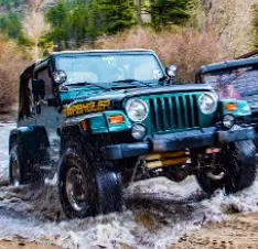 A jeep driving through some water on the road