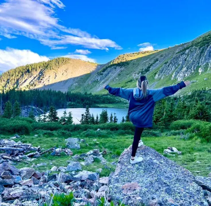 A person standing on top of a rock in the middle of a field.